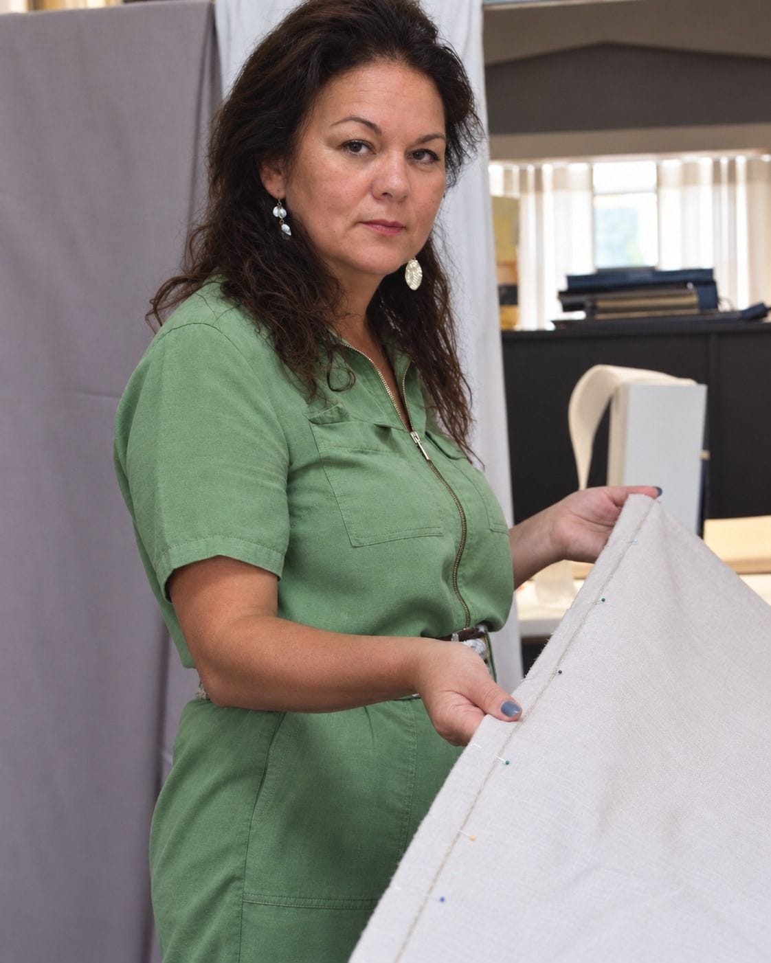 Elisabete Cardoso, CEO do Atelier Millet, de vestido verde, a prender com alfinetes a orla de um tecido de linho no atelier